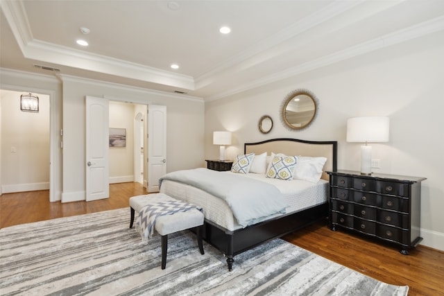 bedroom featuring wood-type flooring, crown molding, and a tray ceiling