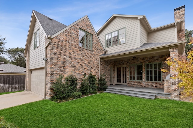 rear view of house with a garage, a yard, and ceiling fan