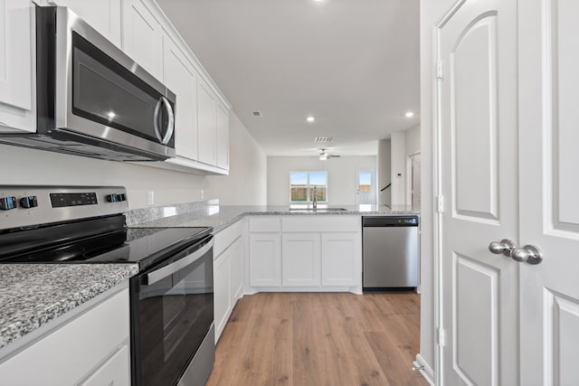 kitchen with white cabinetry, light hardwood / wood-style floors, stainless steel appliances, and sink