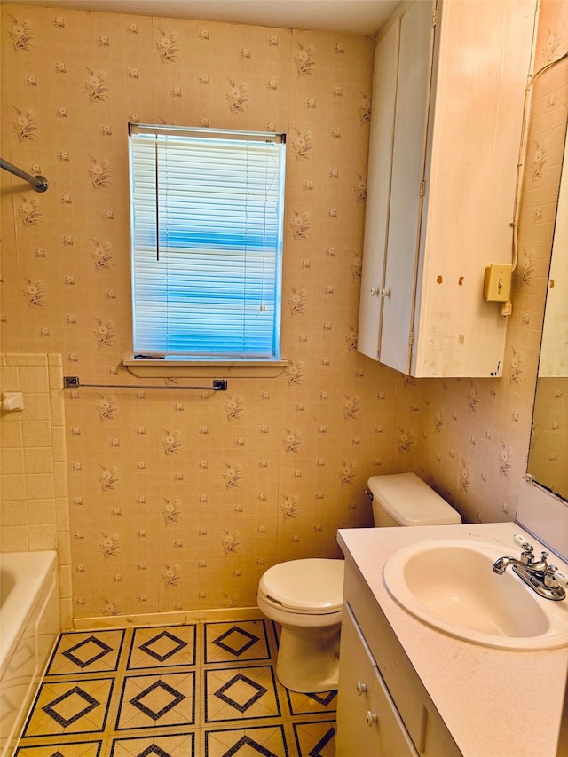 bathroom with a bathing tub, toilet, vanity, and tile patterned floors