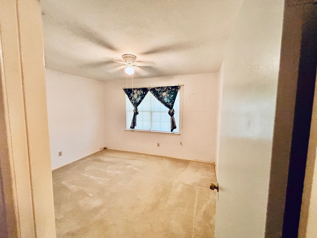 spare room featuring ceiling fan, a textured ceiling, and light colored carpet