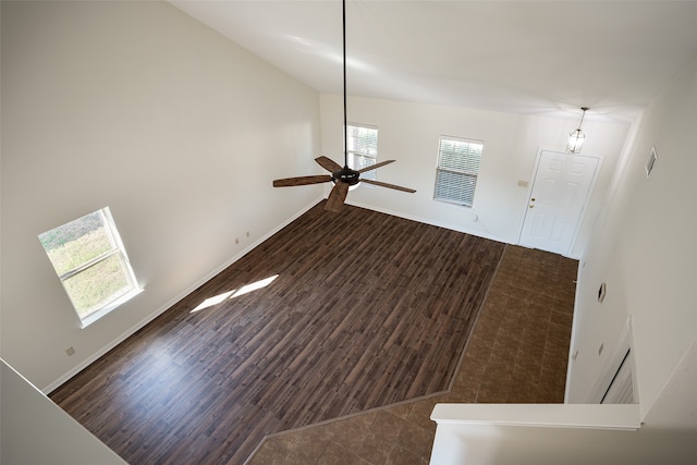 unfurnished living room with ceiling fan, dark wood-type flooring, and a wealth of natural light