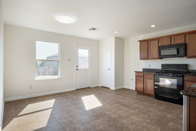 kitchen with dark stone countertops, black appliances, and light tile patterned floors