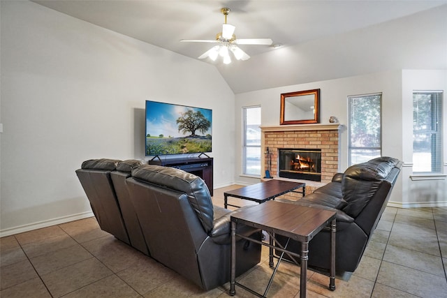 tiled living room featuring vaulted ceiling, a brick fireplace, and ceiling fan