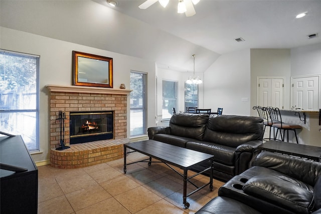 tiled living room with lofted ceiling, a wealth of natural light, a brick fireplace, and ceiling fan with notable chandelier