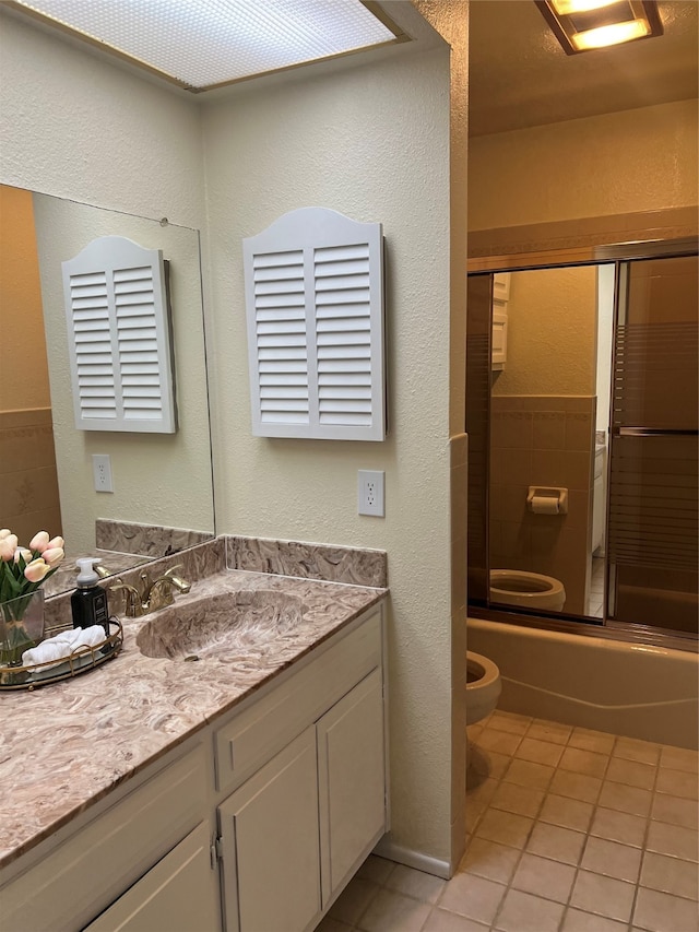 full bathroom featuring vanity, toilet, tile patterned flooring, and bath / shower combo with glass door