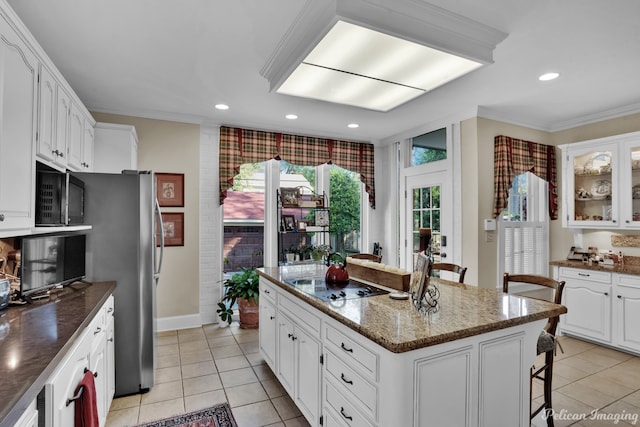 kitchen featuring a kitchen bar, a center island, black electric cooktop, white cabinetry, and crown molding