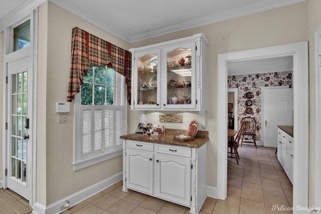 bar with ornamental molding, white cabinets, dark stone counters, and light tile patterned floors