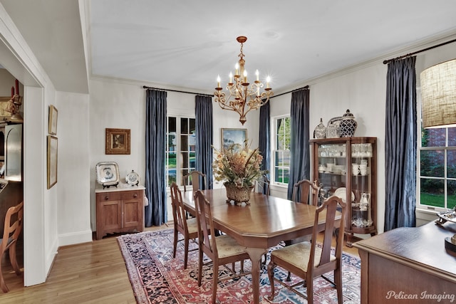 dining space featuring ornamental molding, a notable chandelier, and light wood-type flooring