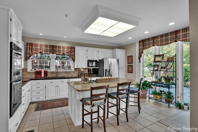 kitchen with stainless steel appliances, tasteful backsplash, a center island, and white cabinets