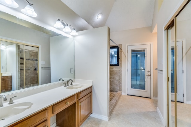 bathroom with vanity, vaulted ceiling, tile patterned flooring, tiled shower, and a textured ceiling