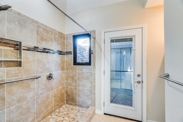 bathroom featuring a tile shower, tile patterned flooring, and a textured ceiling