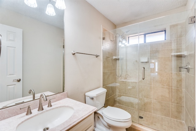 bathroom featuring a textured ceiling, vanity, toilet, and a shower with shower door