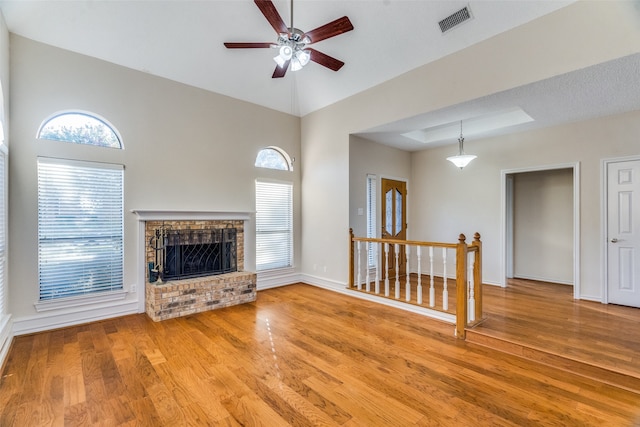 unfurnished living room featuring a fireplace, ceiling fan, light hardwood / wood-style flooring, and a high ceiling