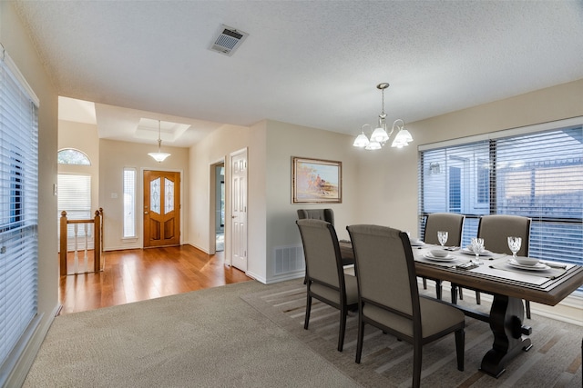 dining room with hardwood / wood-style floors, a textured ceiling, and an inviting chandelier