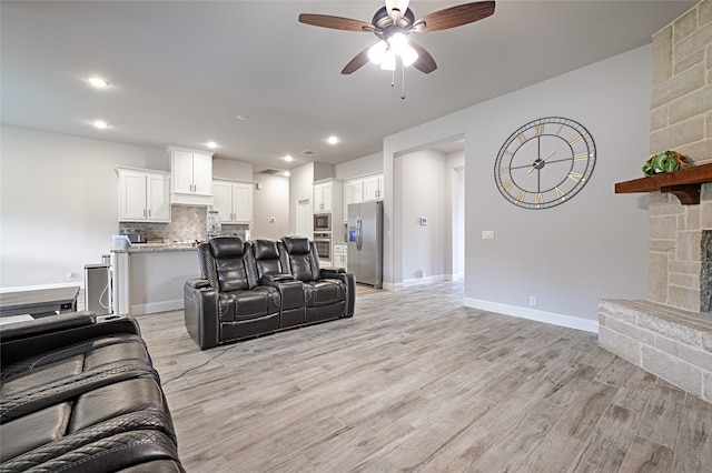 living room featuring light hardwood / wood-style floors, a fireplace, and ceiling fan