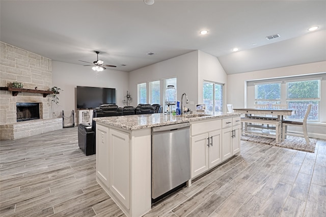 kitchen with a center island with sink, sink, light wood-type flooring, stainless steel dishwasher, and white cabinets