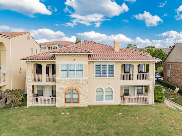 back of house featuring a balcony and a lawn