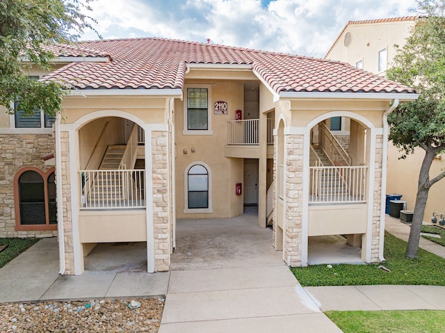 view of front of home with a tile roof, stone siding, and stucco siding