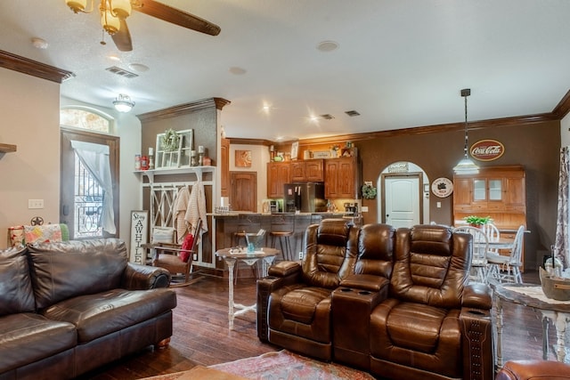 living room with crown molding, a textured ceiling, dark wood-type flooring, and ceiling fan