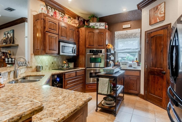 kitchen featuring appliances with stainless steel finishes, sink, light stone counters, crown molding, and light tile patterned floors