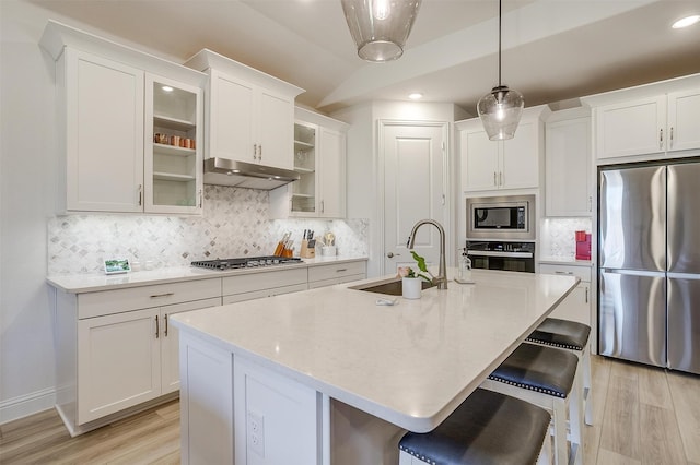 kitchen with sink, an island with sink, stainless steel appliances, decorative backsplash, and light hardwood / wood-style flooring