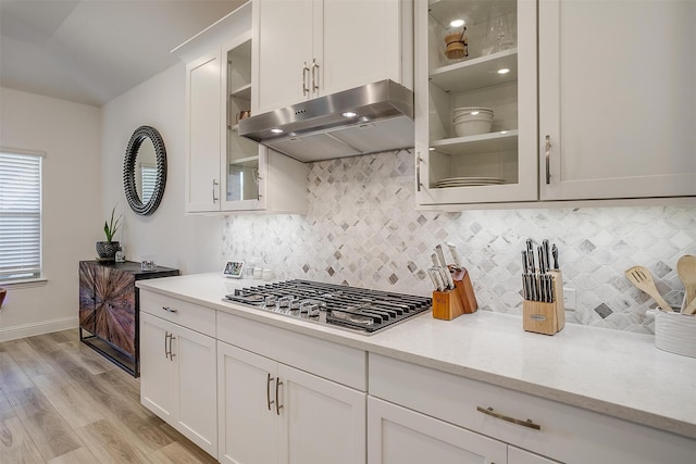 kitchen with white cabinets, light hardwood / wood-style floors, light stone countertops, and stainless steel gas stovetop