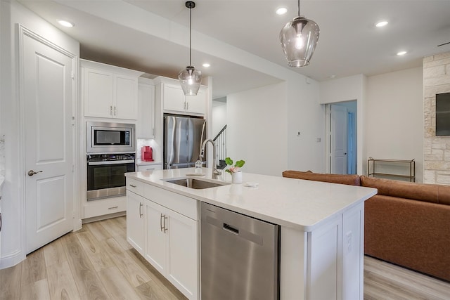 kitchen featuring white cabinetry, appliances with stainless steel finishes, sink, and decorative light fixtures