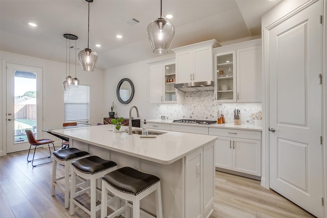 kitchen with sink, a kitchen island with sink, light wood-type flooring, and white cabinets