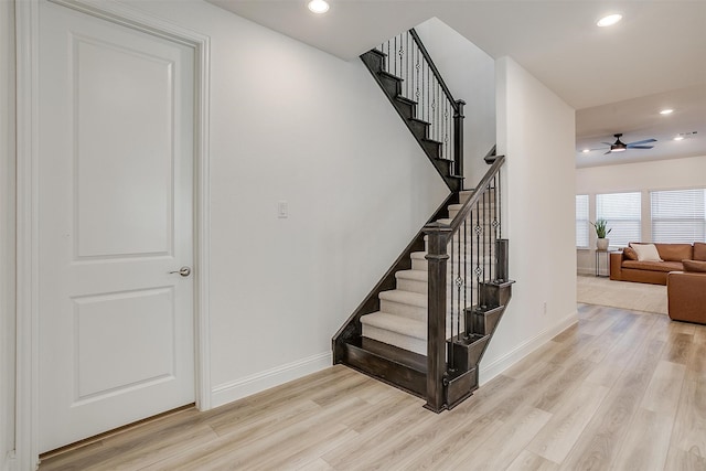 stairway with hardwood / wood-style floors and ceiling fan