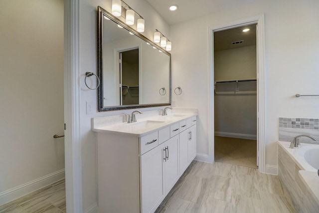 bathroom with vanity and tiled tub