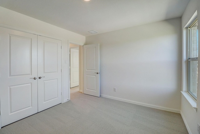 unfurnished bedroom featuring light colored carpet and a closet