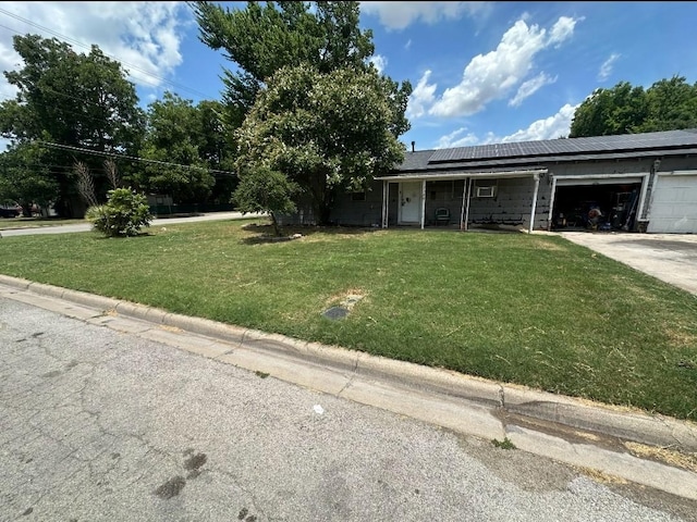 view of front of property with a garage, a front lawn, and solar panels