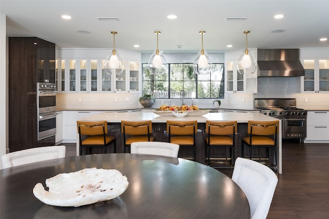 kitchen with white cabinetry, wall chimney range hood, and a kitchen island