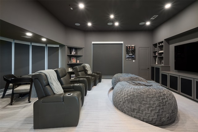 home theater room with a high ceiling, light colored carpet, and built in features