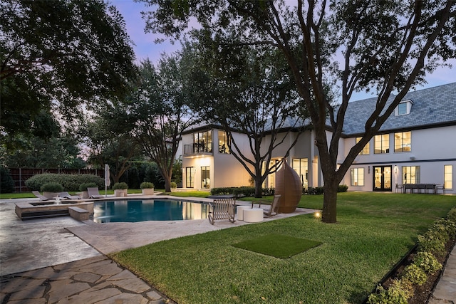 pool at dusk with a yard and a patio