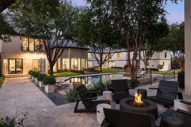 pool at dusk with a patio and a fire pit