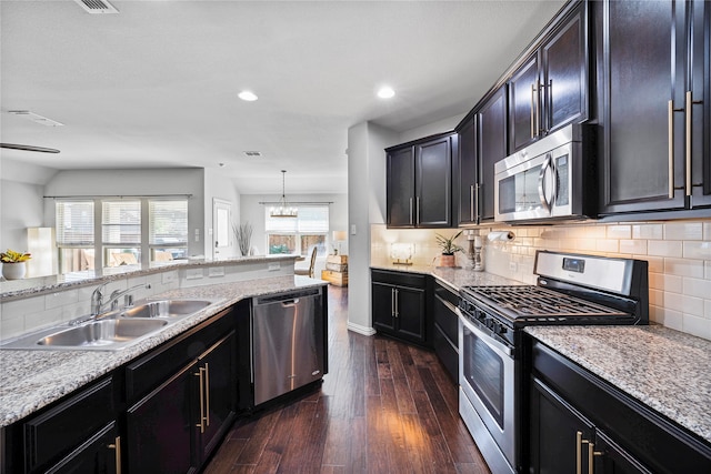 kitchen featuring light stone countertops, sink, stainless steel appliances, dark hardwood / wood-style floors, and decorative light fixtures