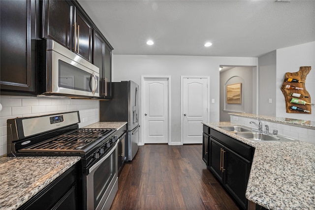 kitchen with light stone countertops, appliances with stainless steel finishes, dark hardwood / wood-style flooring, tasteful backsplash, and sink