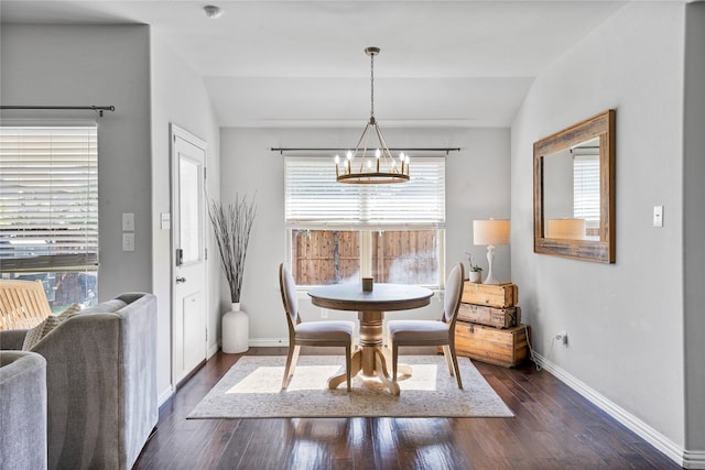 dining room with dark hardwood / wood-style floors, lofted ceiling, and a chandelier