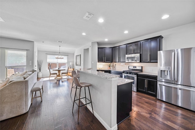 kitchen featuring light stone countertops, appliances with stainless steel finishes, dark hardwood / wood-style flooring, and pendant lighting