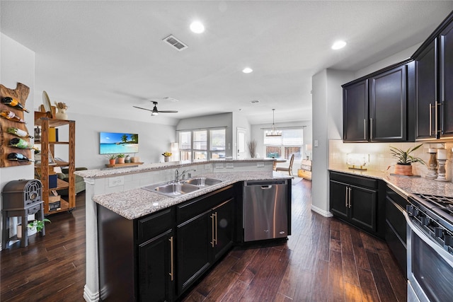 kitchen with sink, dark hardwood / wood-style flooring, decorative light fixtures, a kitchen island with sink, and appliances with stainless steel finishes