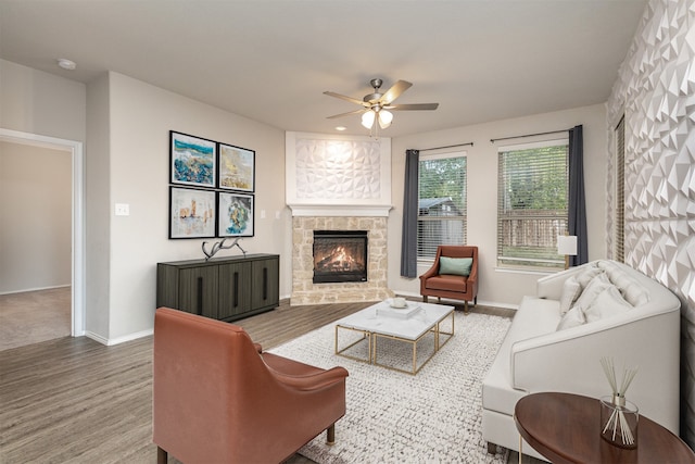 living room with a stone fireplace, ceiling fan, and hardwood / wood-style floors