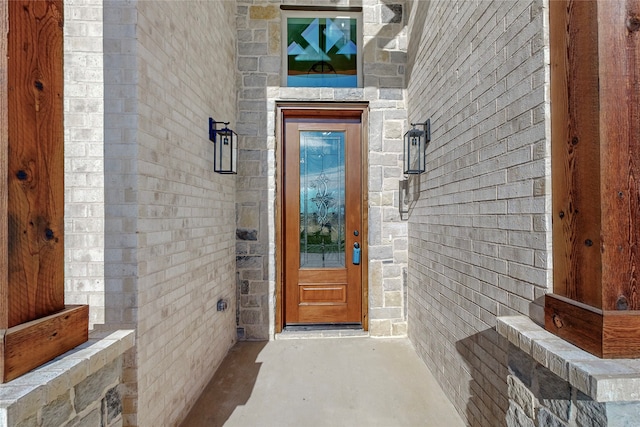 doorway to property featuring stone siding and brick siding