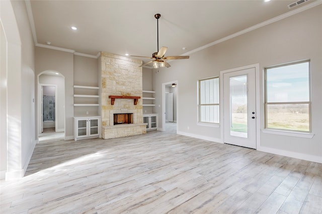 unfurnished living room featuring a stone fireplace, wood finished floors, baseboards, built in features, and ornamental molding