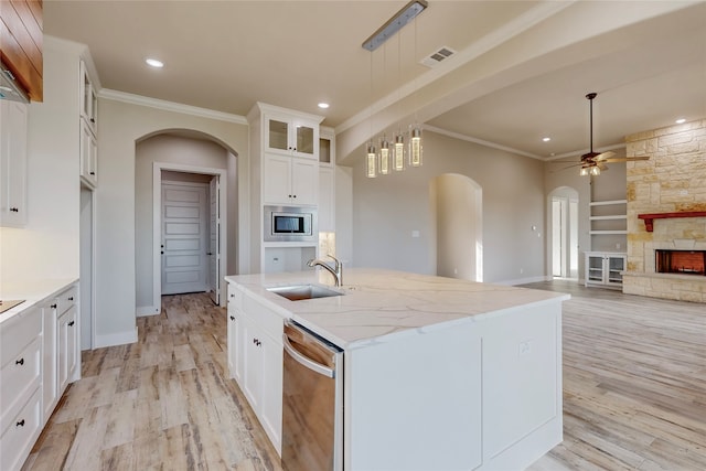 kitchen featuring a stone fireplace, a sink, visible vents, appliances with stainless steel finishes, and light wood finished floors