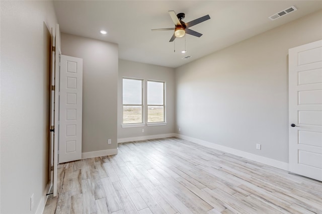 unfurnished room featuring baseboards, light wood finished floors, visible vents, and a ceiling fan