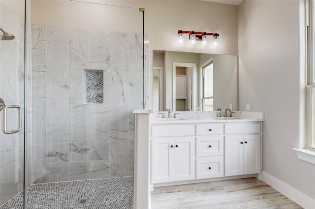 bathroom with double vanity, a stall shower, a sink, and baseboards