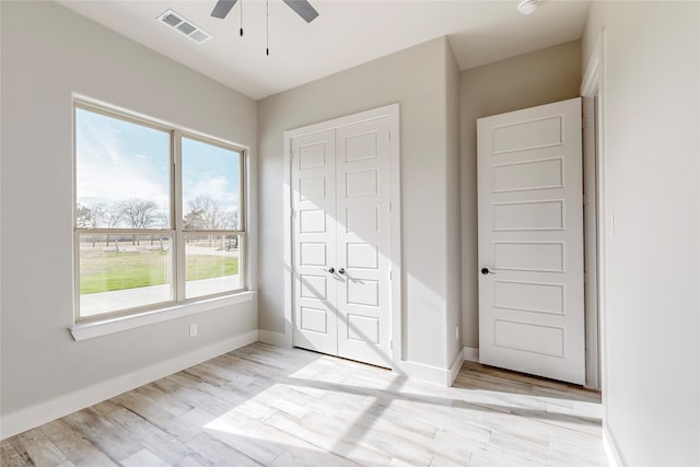 unfurnished bedroom featuring light wood-style floors, visible vents, baseboards, and a ceiling fan