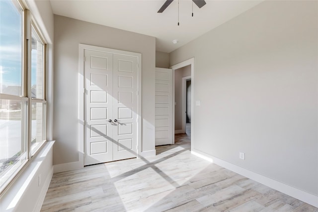 unfurnished bedroom featuring a ceiling fan, light wood-style flooring, and baseboards